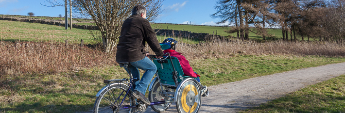 Two people cycling along Peak District trail using a wheelchair bike