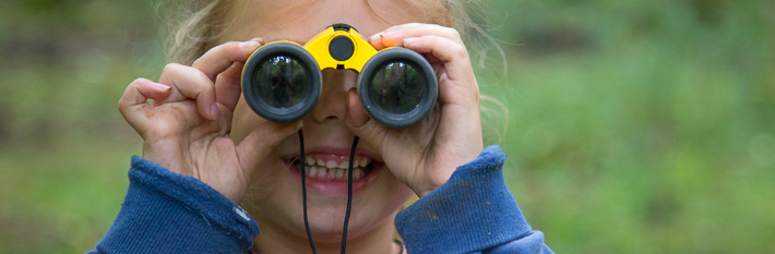 young girl looking through binoculars in the Peak District